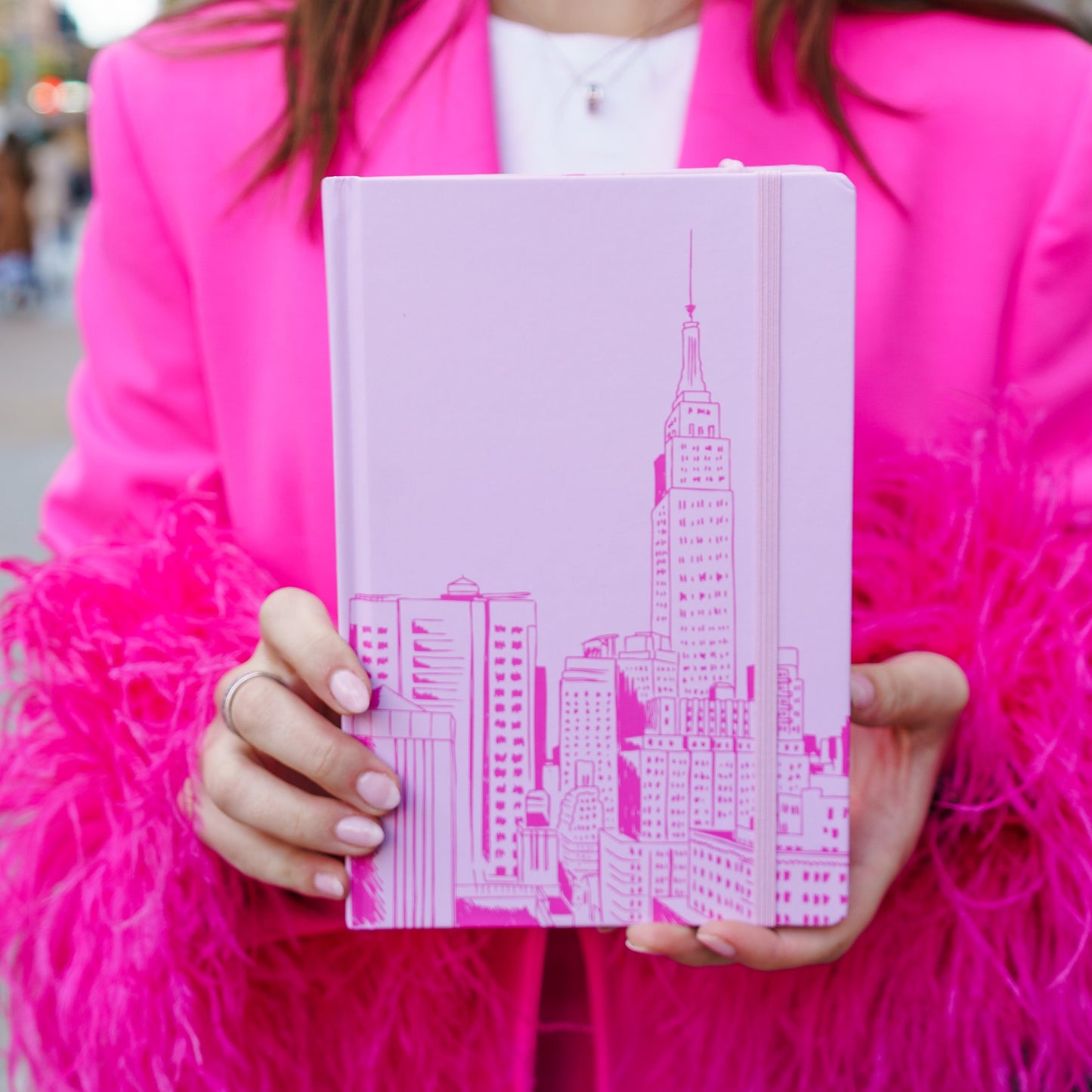 woman holding journal with pink drawing of NYC skyline